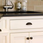 kitchen cabinets painted white under a black countertop
