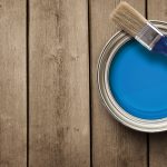 A quart of bright blue paint on a prepped wooden deck.